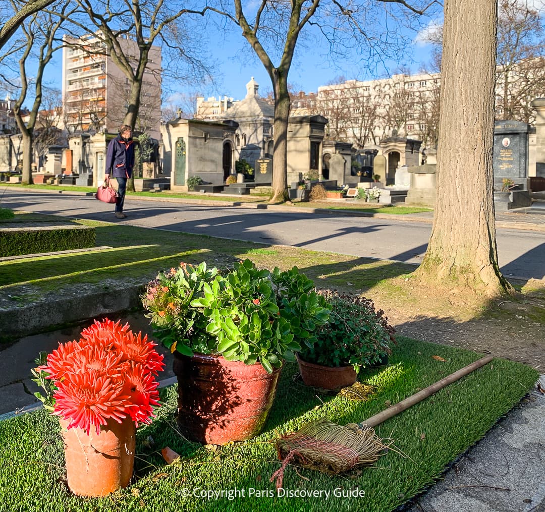 Pots of flowers and a broom for cleaning a grave at Montparnasse Cemetery