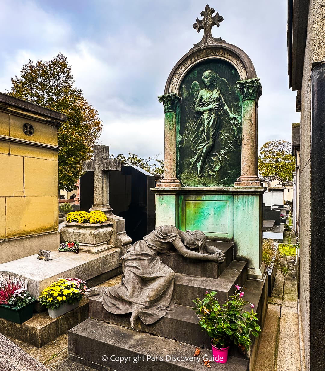 An angel and a weeping woman watch over this memorial in Passy Cemetery, where the pink All Saints Day flowers contrast with the streaks of green from the weathered bronze sculpture