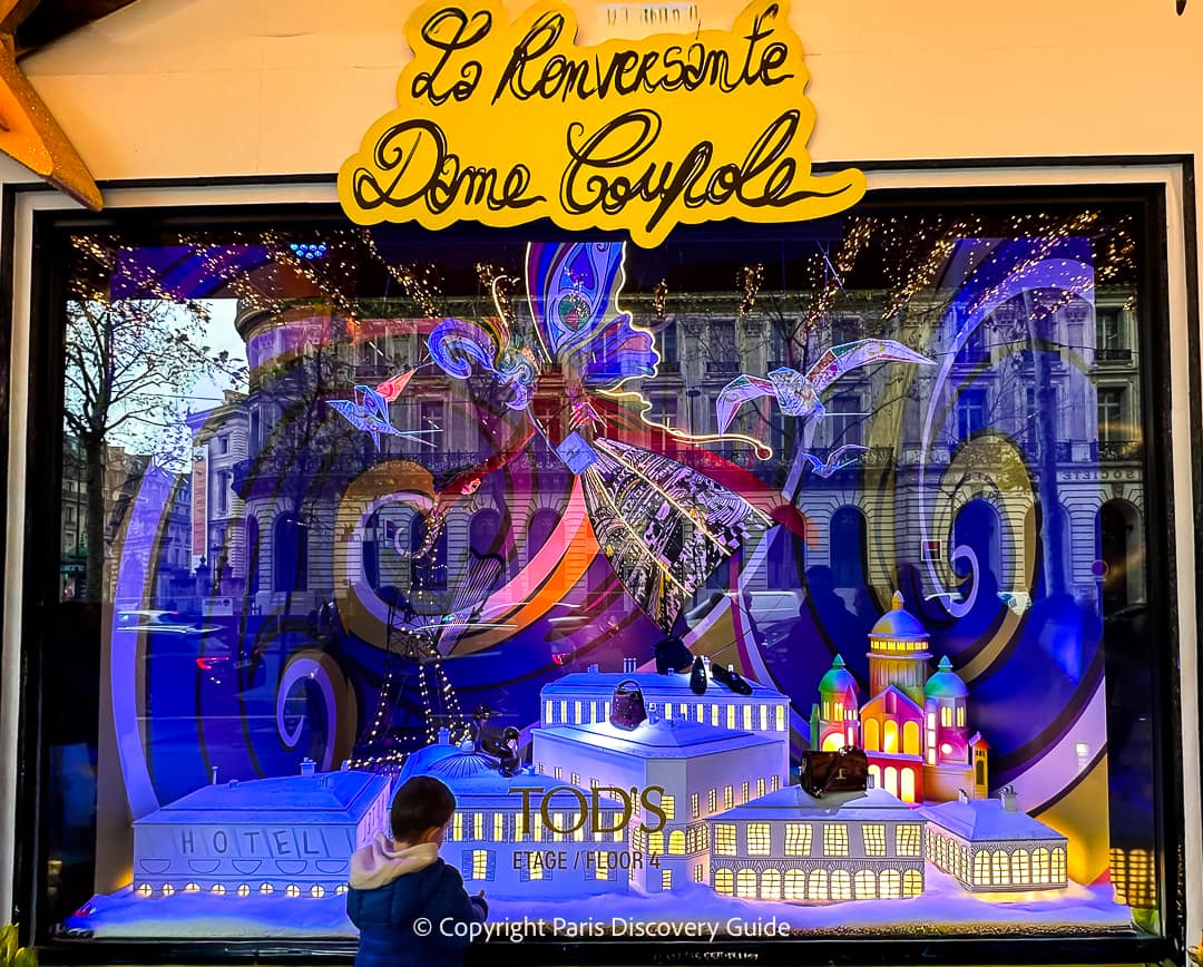 White doves and a fashion-fairy godmother presides over luxury goods and a miniature model of Galeries Lafayette