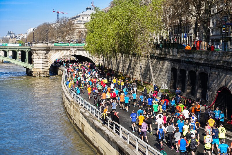 Paris Marathon runners along the Seine River and Notre Dame Bridge